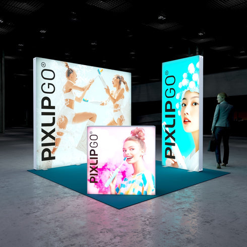 A frontal view of the Pixlip GO booth, emphasizing its playful and bright theme. The large illuminated wall features two women in an energetic foam battle, while the side panel highlights a portrait of a woman with a clean and fresh aesthetic. The counter displays a cheerful woman with a toothbrush in hand. A person stands nearby.