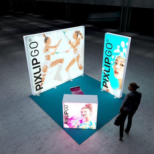 A dynamic perspective of the Pixlip GO booth, showcasing the illuminated panels from various angles. The main wall portrays an exciting foam fight, complemented by vibrant images on the side and counter panels. A person is seen walking toward the booth.