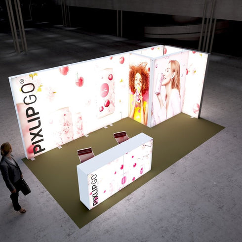 A bright and inviting Pixlip GO exhibition booth with a focus on fruity beverages. The illuminated panels feature vibrant images of cherries, drink cans, and smiling individuals enjoying beverages. The setup includes a central counter with matching graphics. A visitor approaches the booth.