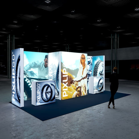 An angled perspective of the exhibition setup. The booth’s vibrant visuals highlight cycling adventures, with central and side panels illuminated to attract attention. The dark flooring complements the bright, high-quality graphics, creating an engaging and modern display.