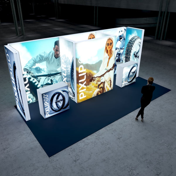 A vibrant exhibition booth showcasing a dynamic display featuring outdoor adventure and biking imagery. The central panel highlights a confident female cyclist, while side panels display close-ups of rugged mountain bike tires and an athlete in action. The booth is set up on a dark blue carpet, creating a striking contrast.