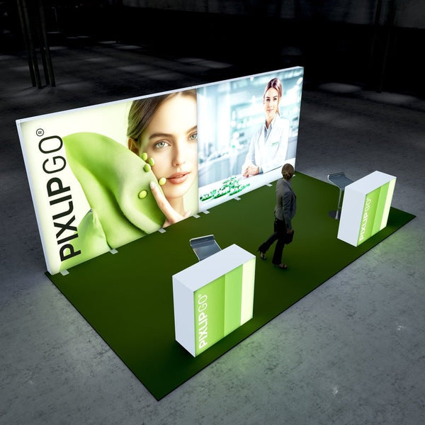 A Pixlip GO exhibition booth with a clean and eco-focused theme. The large illuminated panels feature a close-up of a woman with green peas and a fabric texture, alongside another panel depicting a lab professional in a sterile environment. The setup includes counters with a green and white color scheme. A person observes the booth.