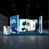Front view of a trade show stand showcasing science visuals, including microscopes and digital screens displaying microscopic imagery. The illuminated display is branded with 'PIXLIP GO' logos on a blue backdrop.