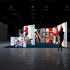 A vibrant exhibition booth setup with a large illuminated panel featuring a bright red character performing tricks on a skateboard on a staircase. The surrounding panels showcase skateboards and dynamic action shots, creating an energetic and playful atmosphere.