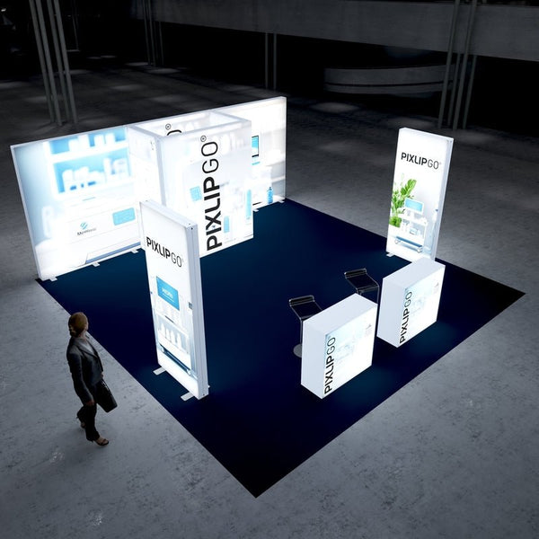 A top-down perspective of the PIXLIP GO trade show setup with glowing light panels showcasing medical graphics and green plant elements. Two illuminated counters stand in front, and the surrounding area has a professional atmosphere.