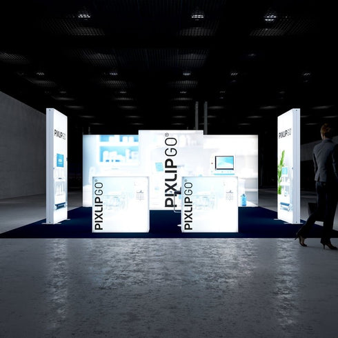 A frontal view of the PIXLIP GO trade show booth, highlighting backlit displays with medical equipment and scientific graphics. The arrangement emphasizes brightness and clarity, with a sleek navy blue carpet completing the setup.