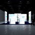 A frontal view of the PIXLIP GO trade show booth, highlighting backlit displays with medical equipment and scientific graphics. The arrangement emphasizes brightness and clarity, with a sleek navy blue carpet completing the setup.
